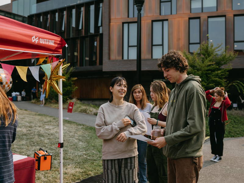 Students are lining up next to a popup tent and smiling at each other.