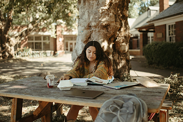 A student sitting at a picnic bench.