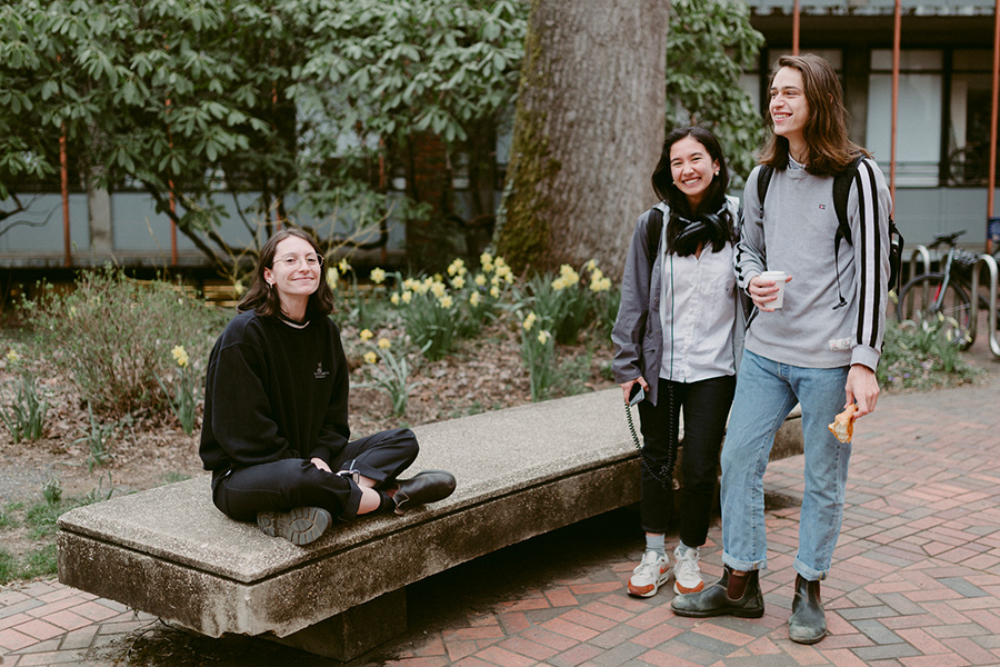 Reed students gathered around an outdoor bench.