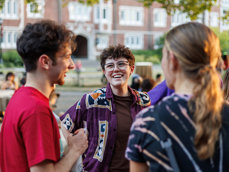 Three students talking outside during an ice cream social.