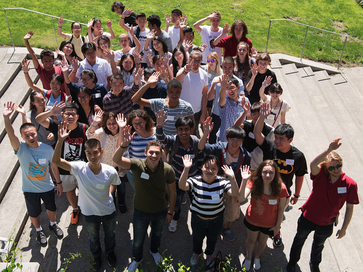 Reed international students gathered on the steps of the performing arts building, waving at the camera