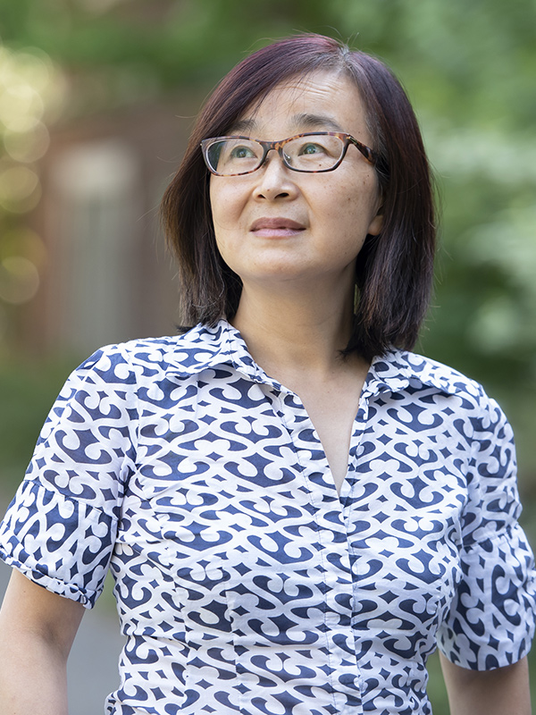 Reed College faculty member, Jing Jiang, looks into the distance in this an outdoor headshot