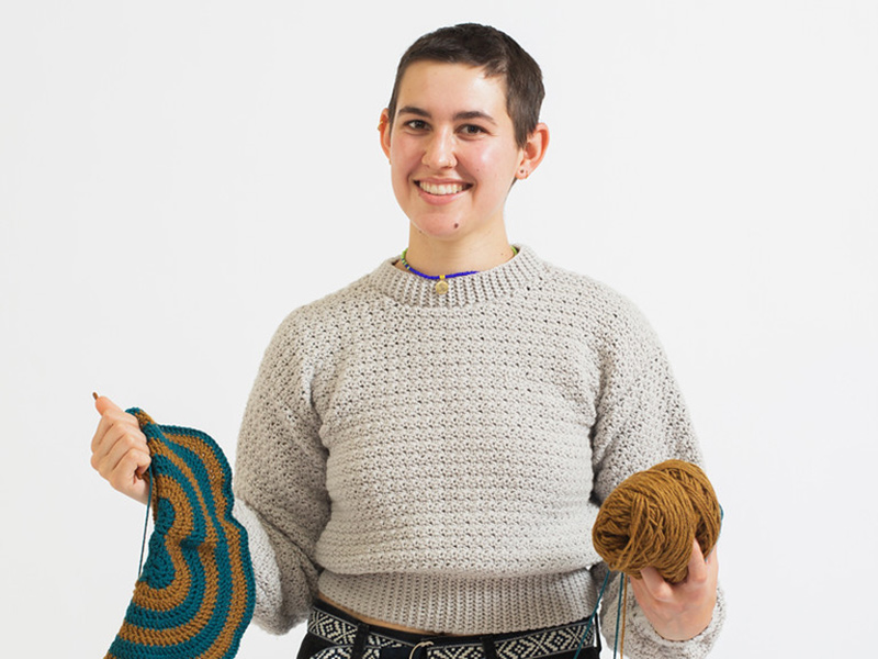 A portrait photo of Elena Carmen Turner, who is holding a crochet project