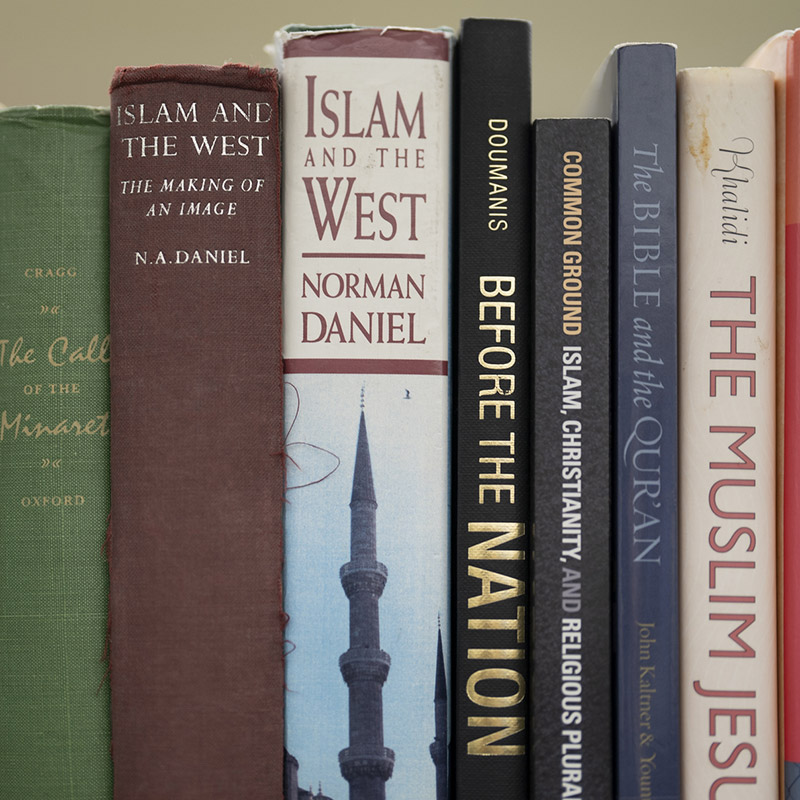 A library bookshelf with books on Islam and Christianity