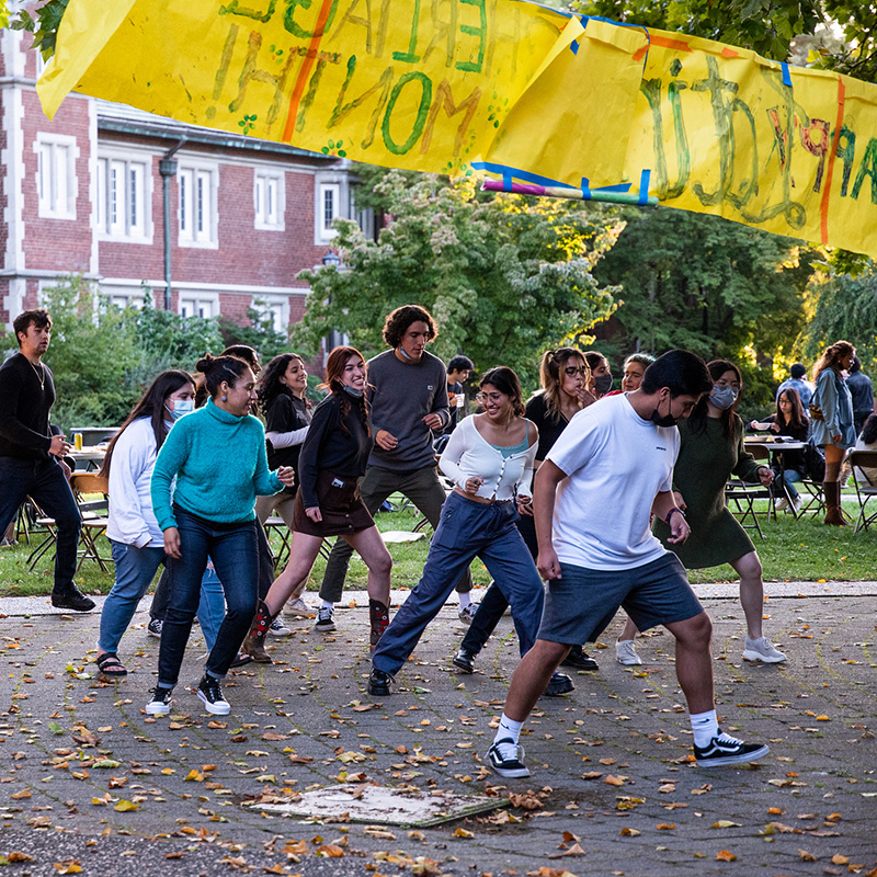 Reed students dance in the Quad with an overhead sign that says Happy Hispanic Heritage Month