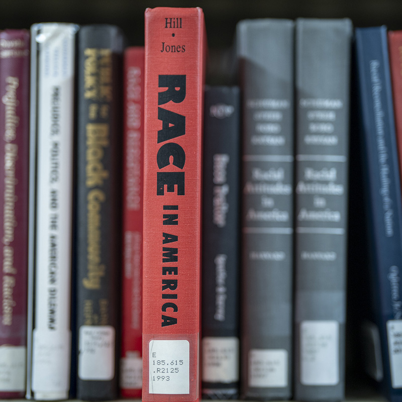 A reference shelf in the library. A red book is pulled halfway out, with a title that reads Race in America.