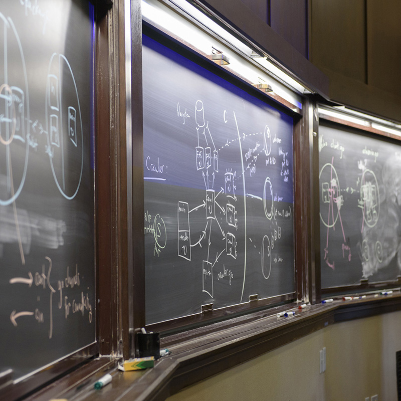 Three connected chalkboards show diagrams in a computer science class