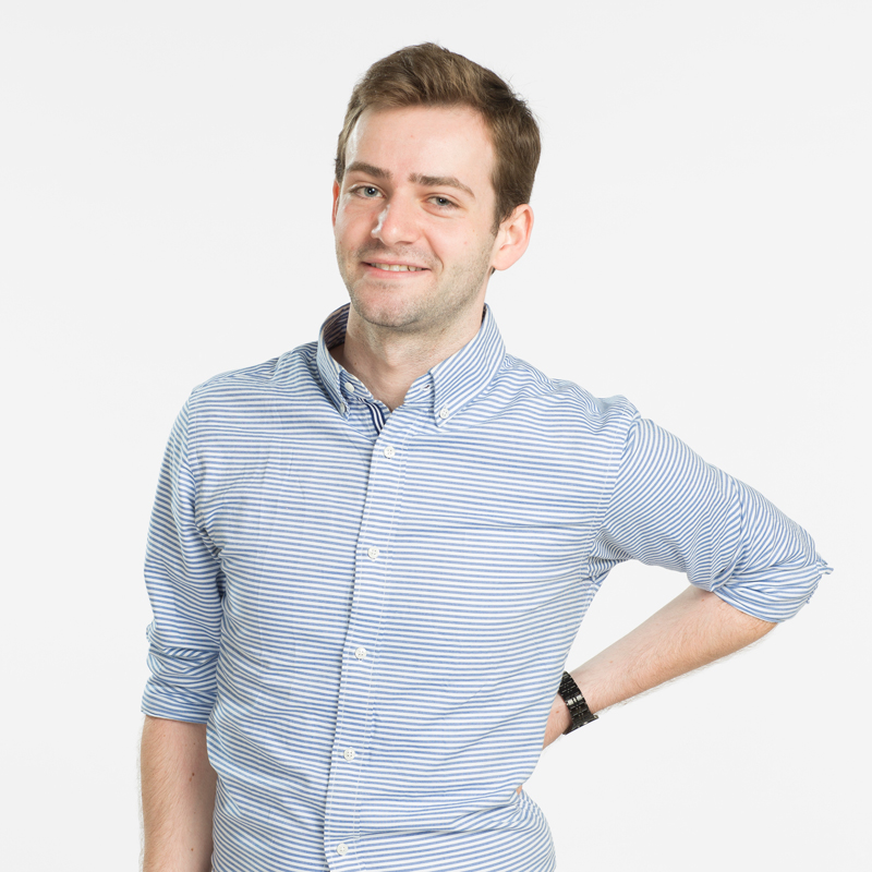 A portrait photo of Reed College student Daniel Kugler wearing a blue-striped button-down shirt