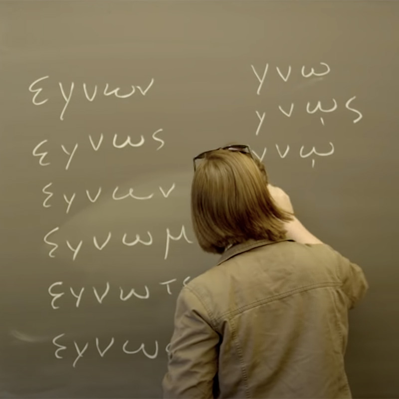 A professor writes with chalk on a board in the classroom