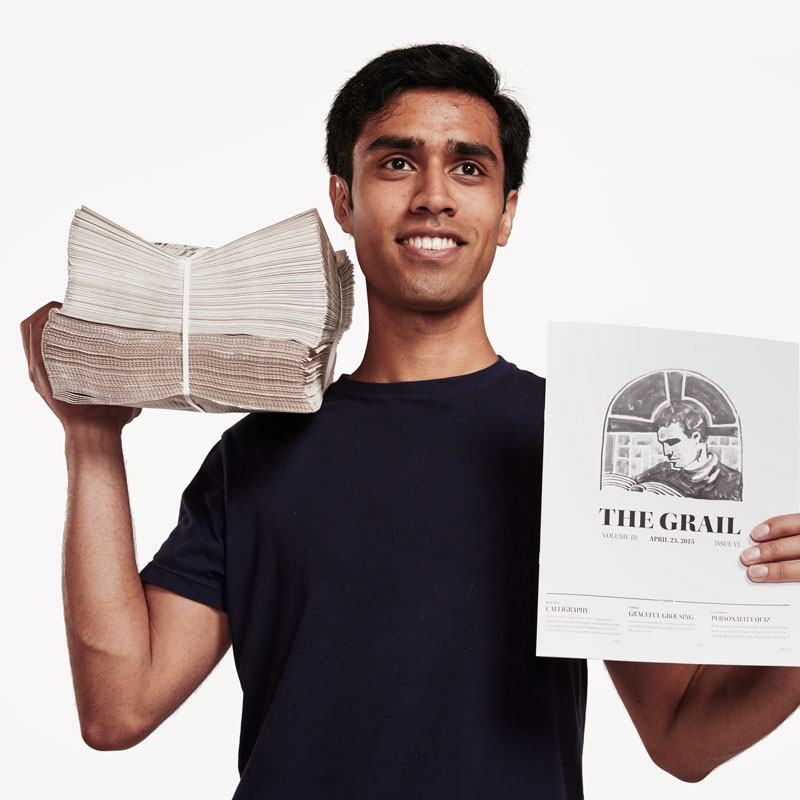 A portrait photo of  Vikram Chan-Herur, who holds up copies of The Grail, a student-run creative magazine