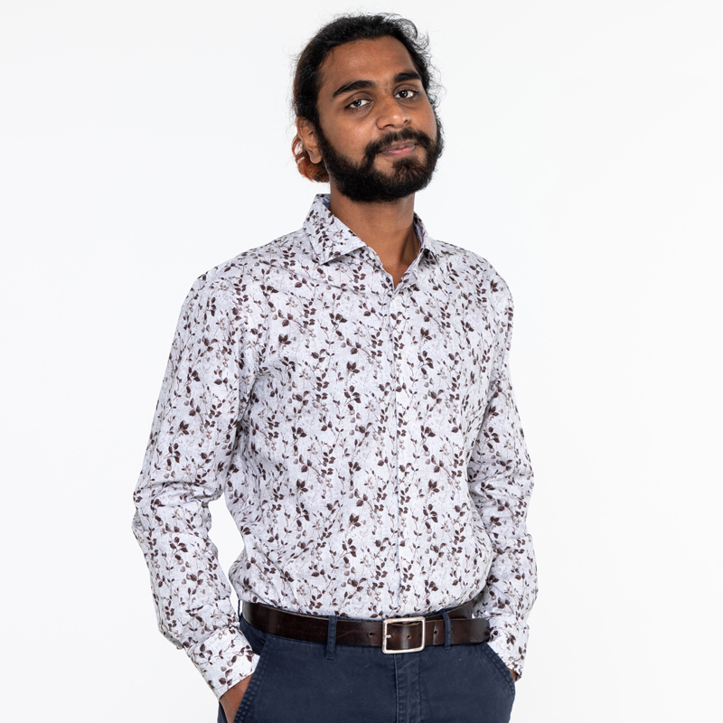 A portrait photo of Abhi Rajshekar, who is wearing a white button-down shirt with a repeated leaf pattern