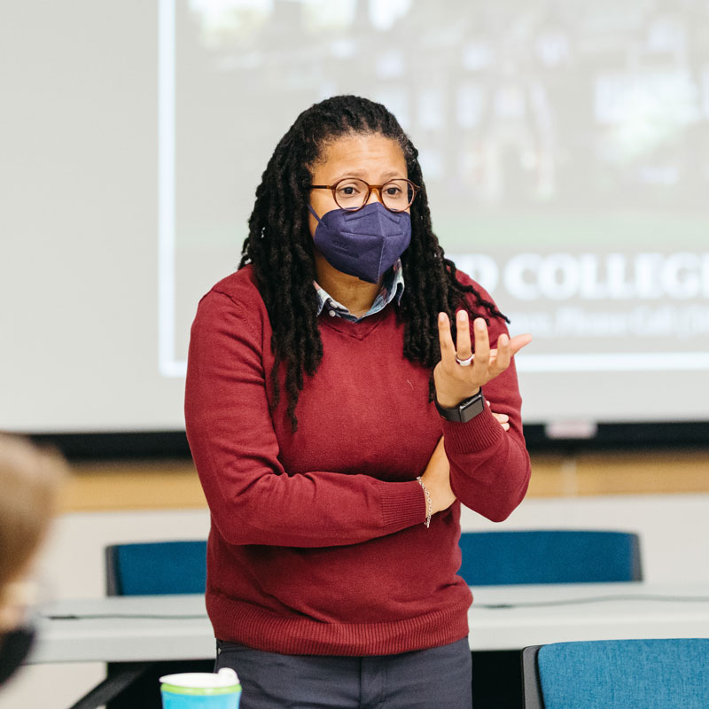 A Reed professor wearing a dark blue face mask lectures to her students