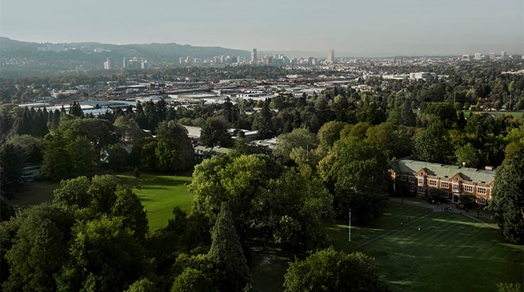 Aerial view of Reed campus with downtown Portland in the distance.