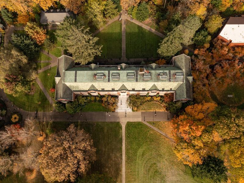 An aerial view of Eliot Hall and the surrounding green lawn and autumn trees. 