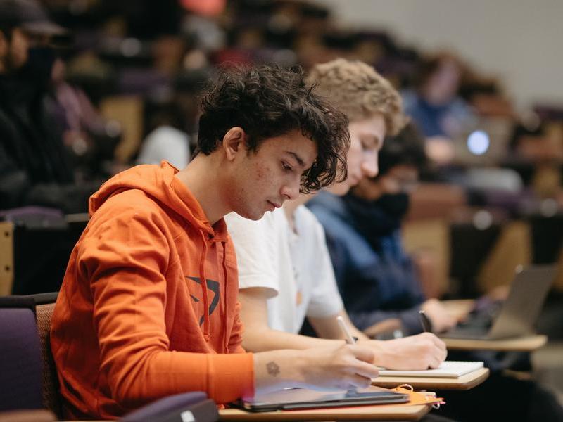 Two students taking notes during a lecture in Vollum lecture hall