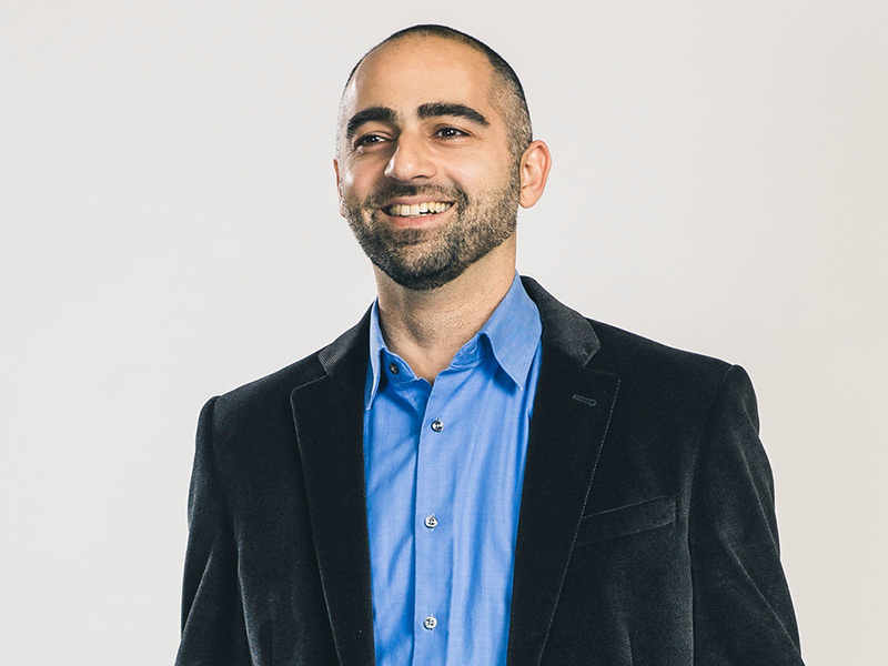 Ali Nouri smiles while posing for a headshot