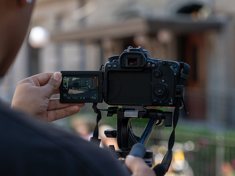 A student reaches for a large volume of a book titled "Film Quarterly" on the shelf of a library.