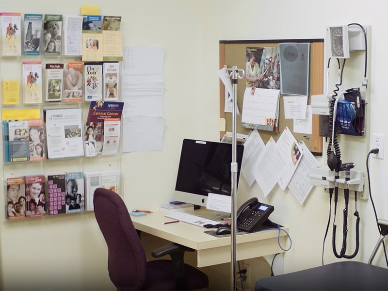 An unoccupied medical station that has a phone and a computer. On the walls are medical equipment and pamphlets