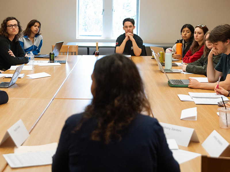 A conference-style classroom with students and professor.