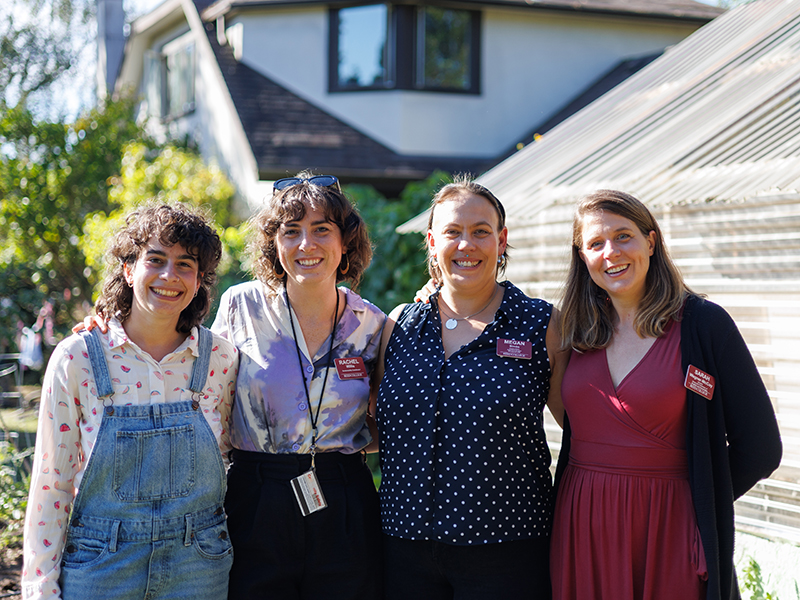 Four Reed staff and faculty members smile and pose for a photo outside of Garden House.