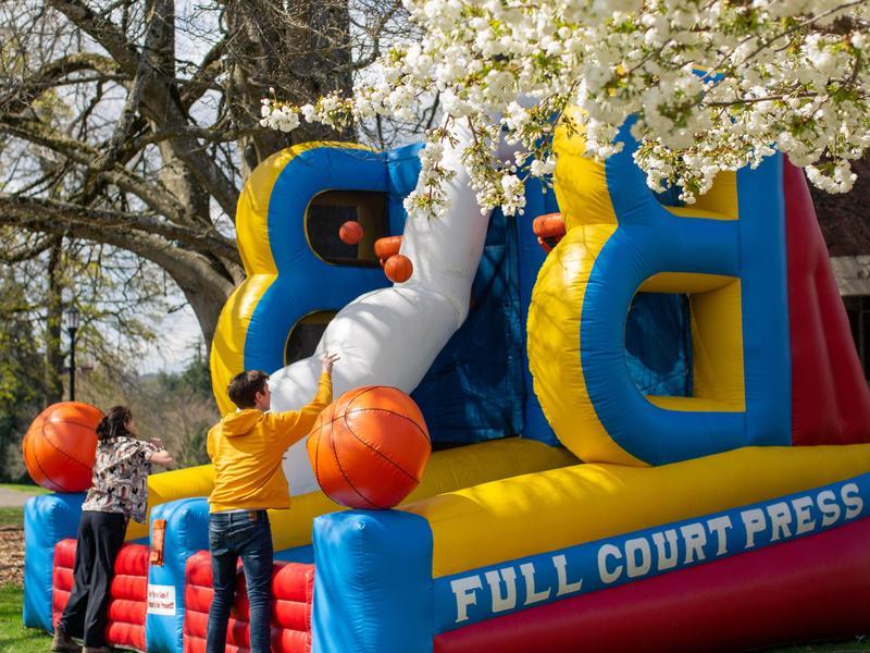 Two students shoot basketballs into large inflatable basketball hoops on the Great Lawn.