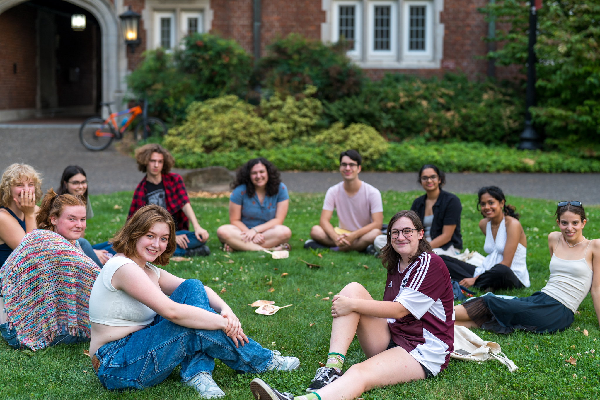 A group of students sitting in a circle on the lawn.
