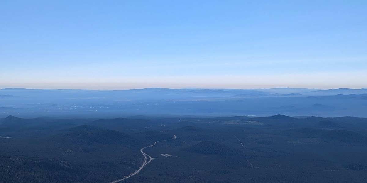 A view of a forested landscape and the horizon beyond from a very high vantage point.