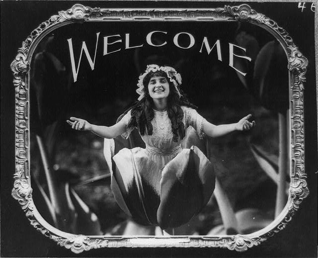 woman emerging from flower saying welcome