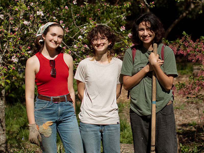 Three students pose outside with gardening tools during Canyon Day.