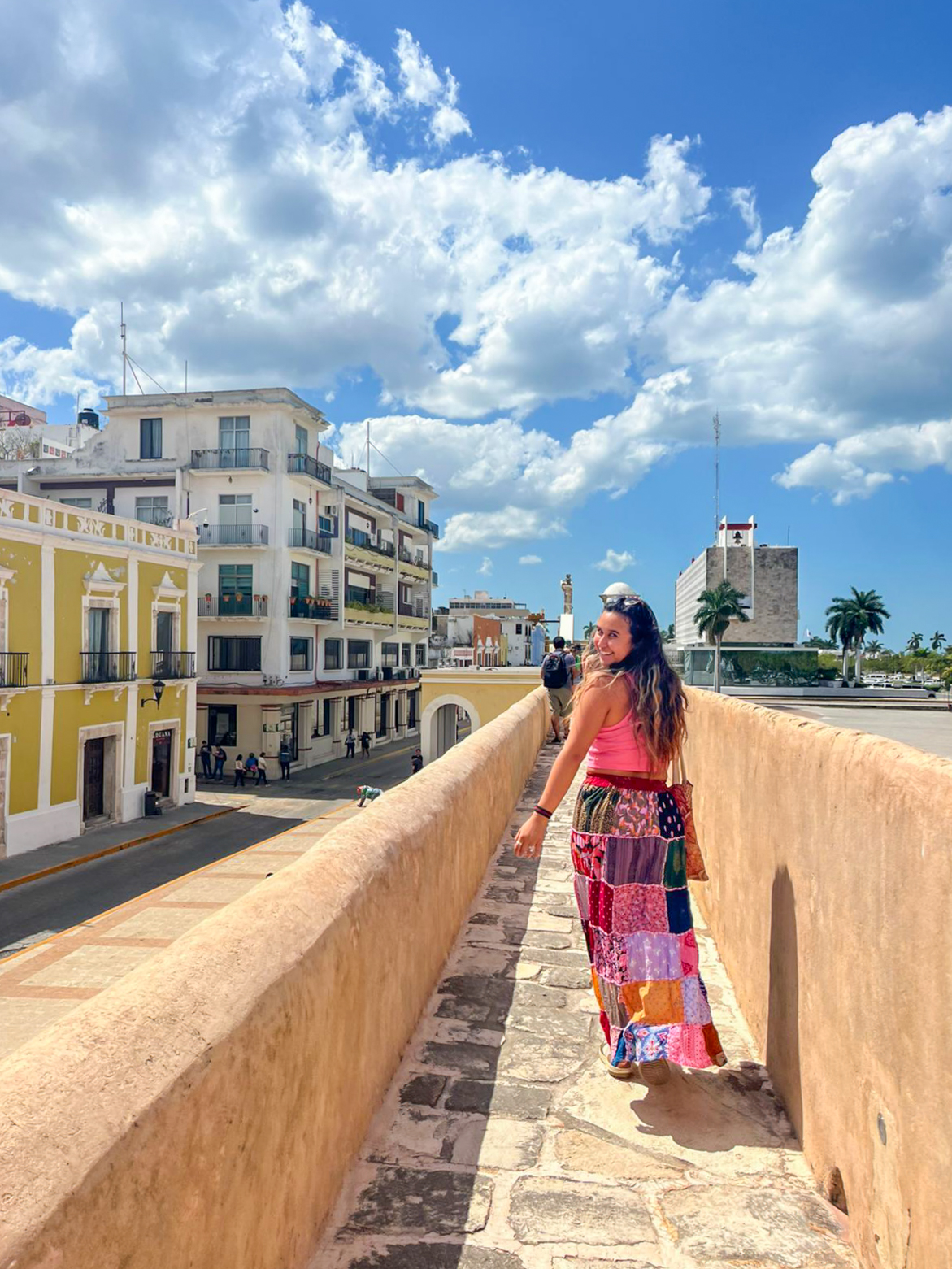 Student turns back to camera while walking in Mérida on a sunny day