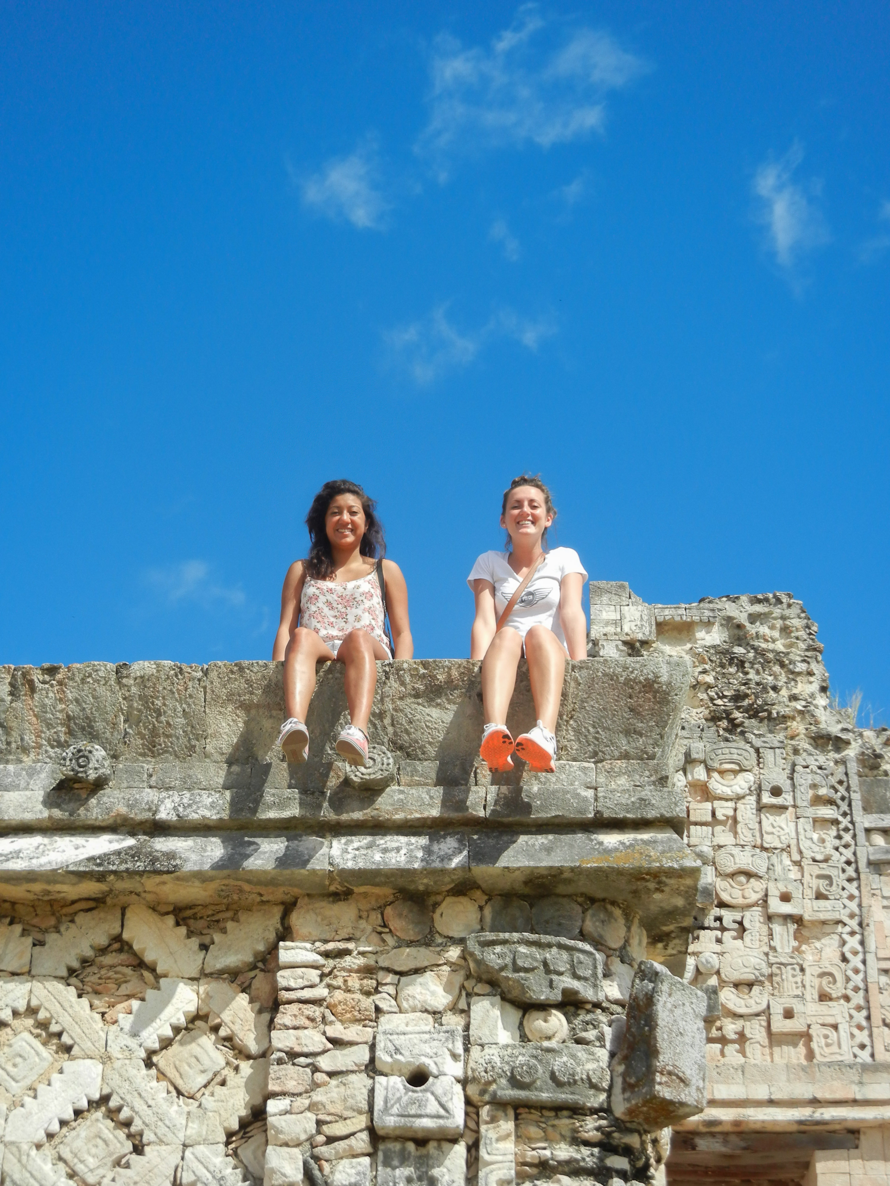Two students sit on a decorated stone wall