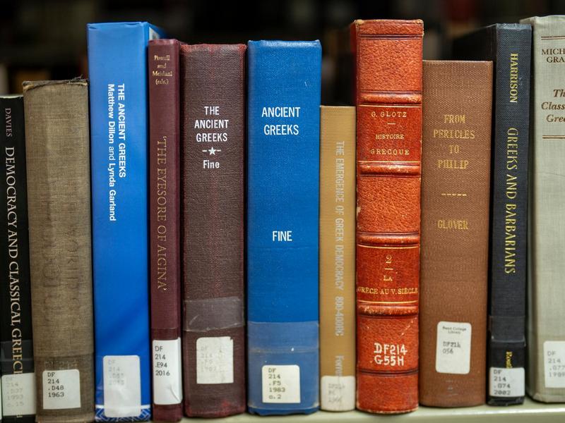 Row of library books about ancient Greece on a bookshelf.