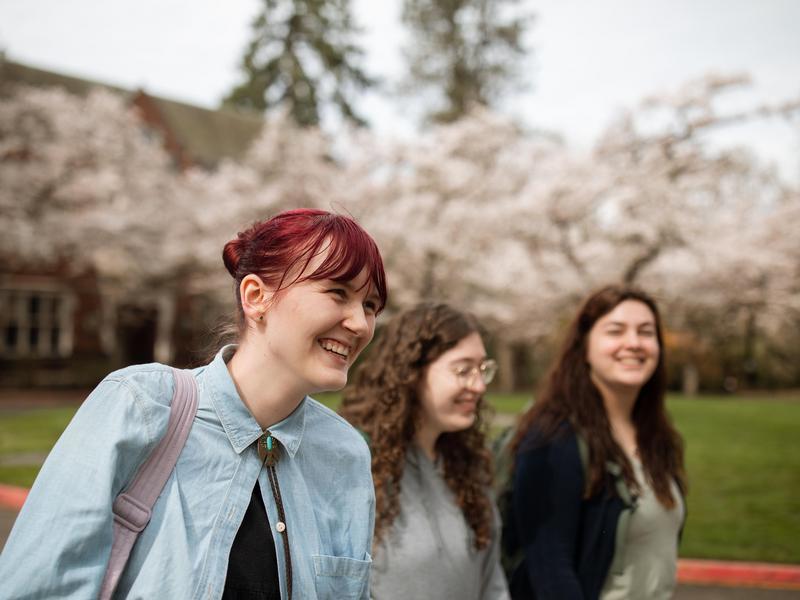 Three students smile while walking on campus.