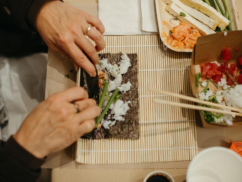 Overhead view of a person making a sushi roll.