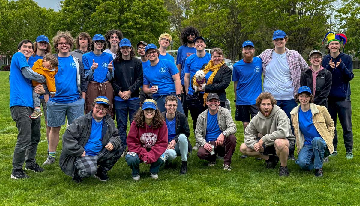 A team photo of the math-stats softball team standing on a grassy field