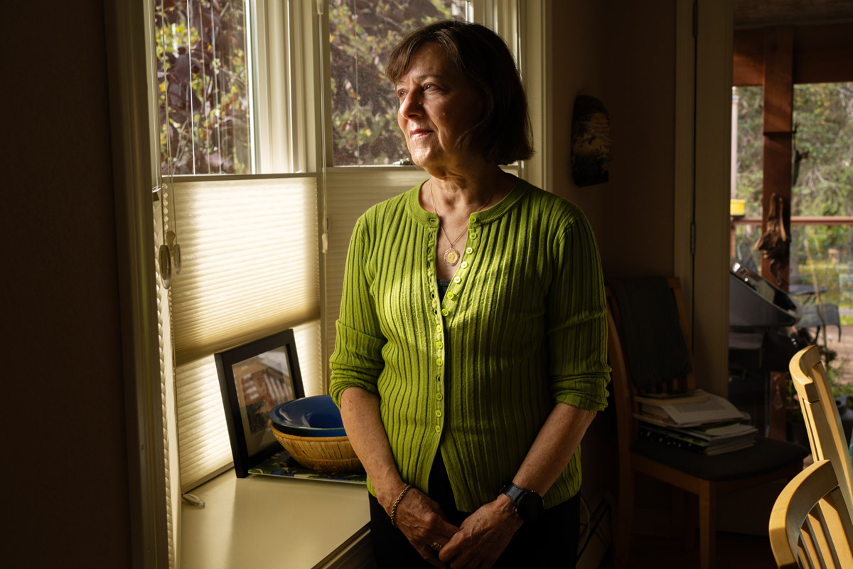 Carla Beam standing in her home and looking out a window.