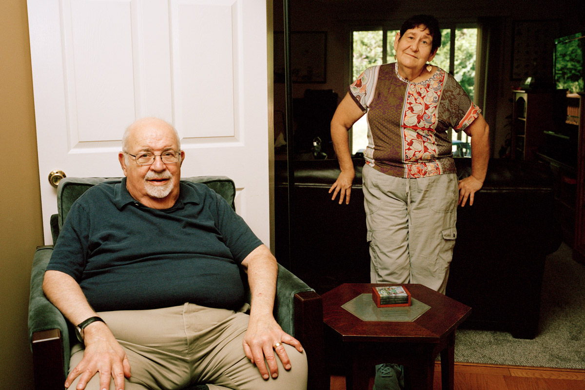 Sheldon Hochheiser sitting in an armchair while Laura Leviton leans against a couch.