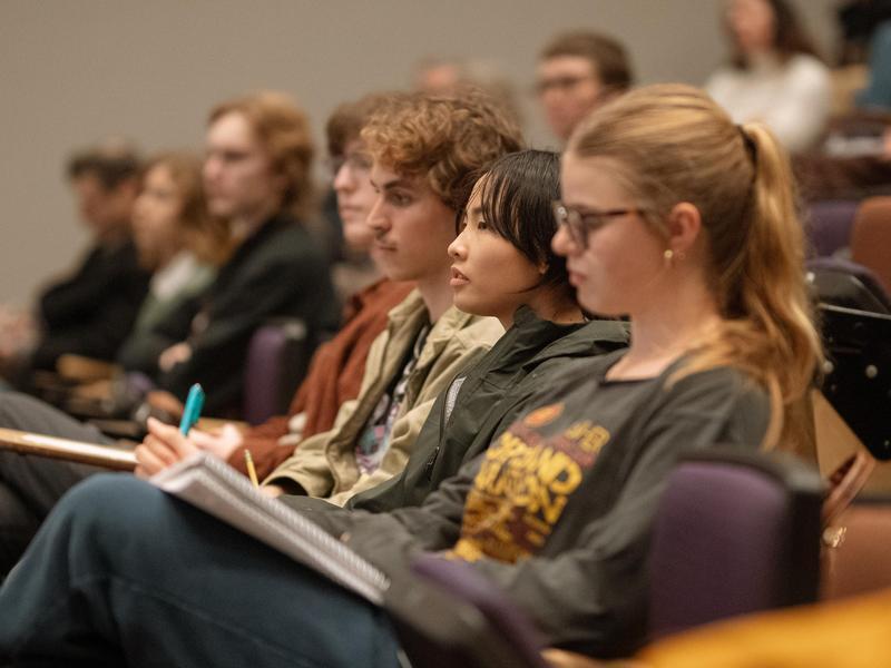 Students sitting and talking notes in a lecture hall.