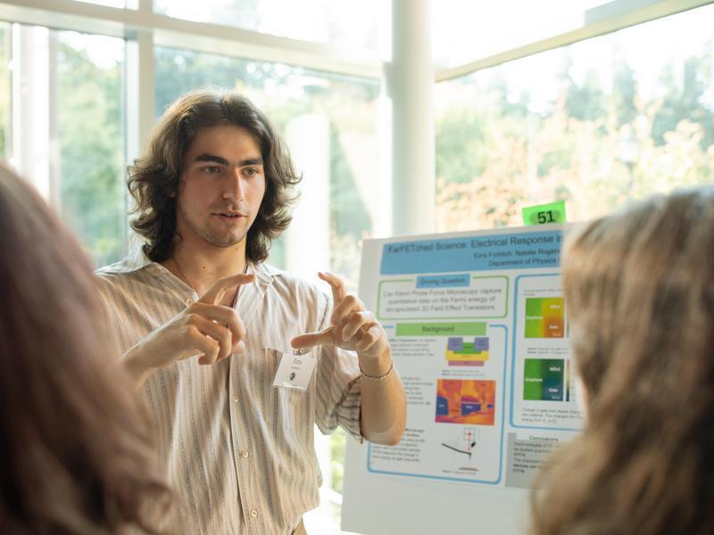 A student presenting a research poster at an event.