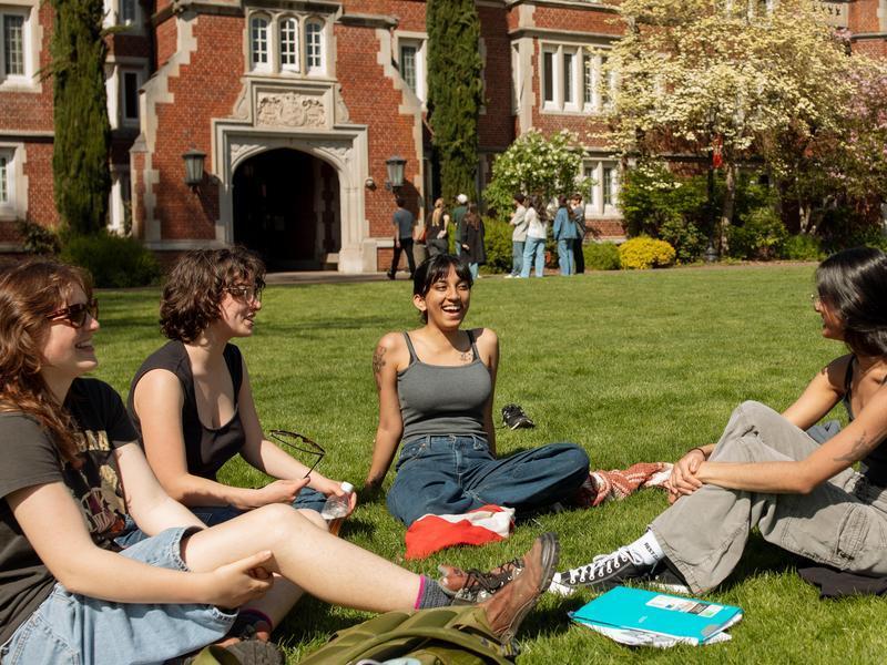 Four students relaxing in the grass on the Great Lawn.