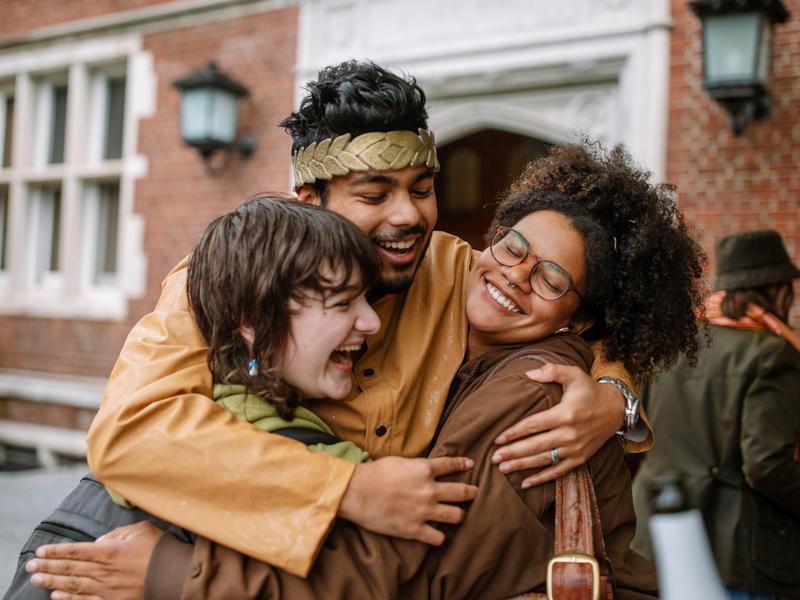 Three students hug outside Eliot Hall during Renn Fayre.