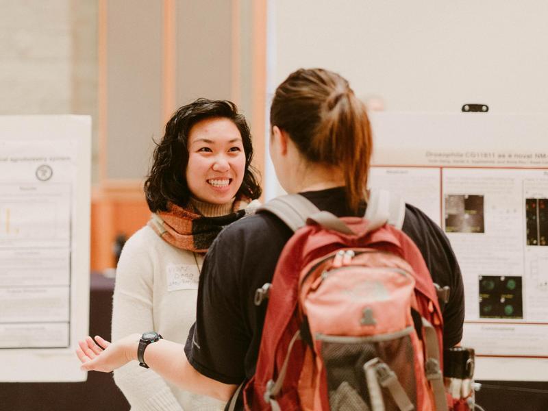 Two people in conversation at a research poster event.