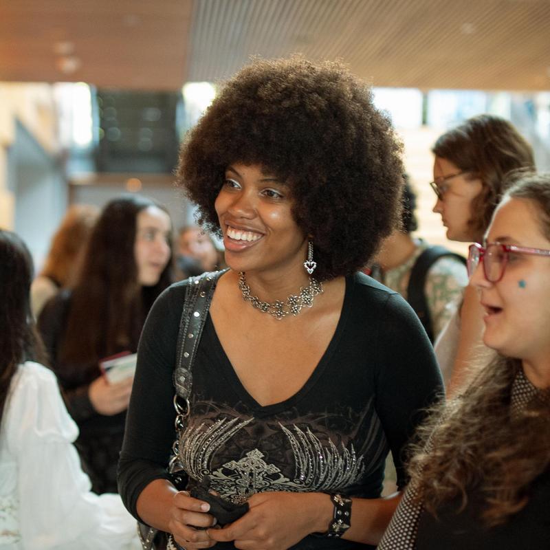 Soraya Mwangi smiling while listening to a peer present research at an event.
