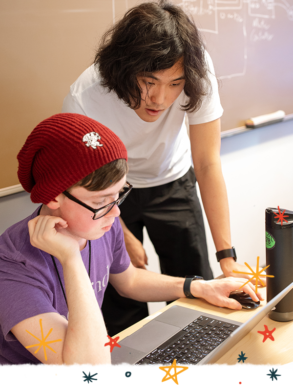 Two students looking at a laptop in a classroom.