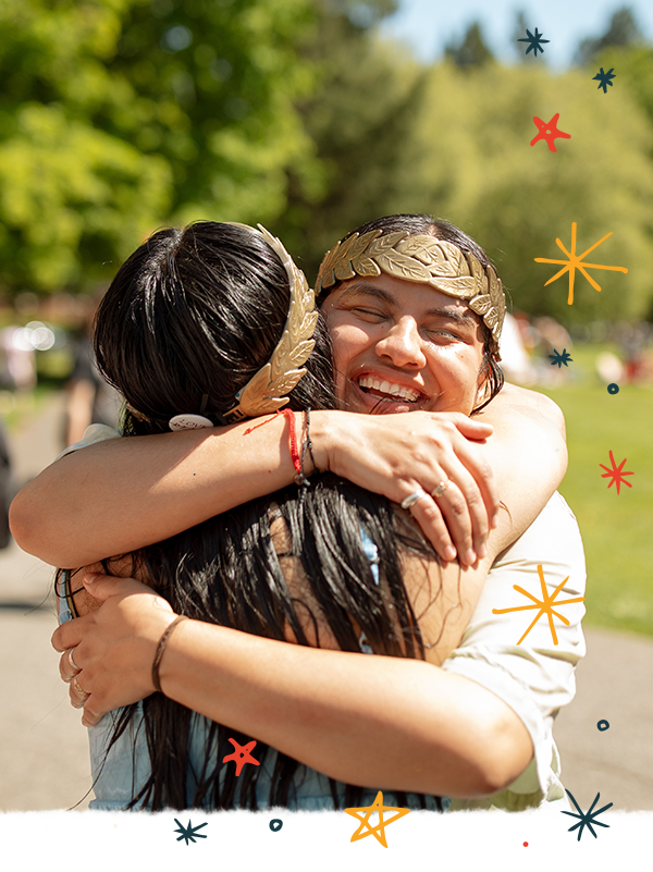 Two students wearing laurels embrace during the thesis celebration.