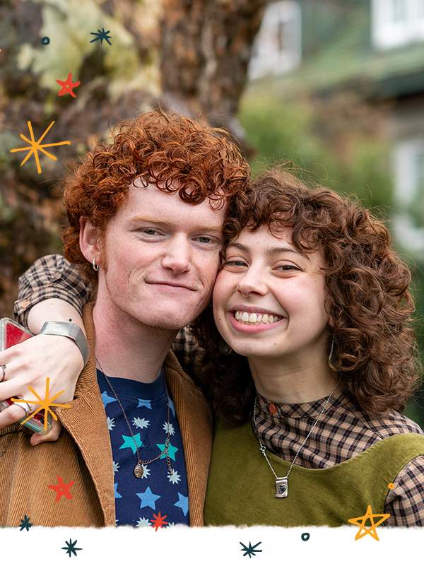 Two students smile for a photo outside.
