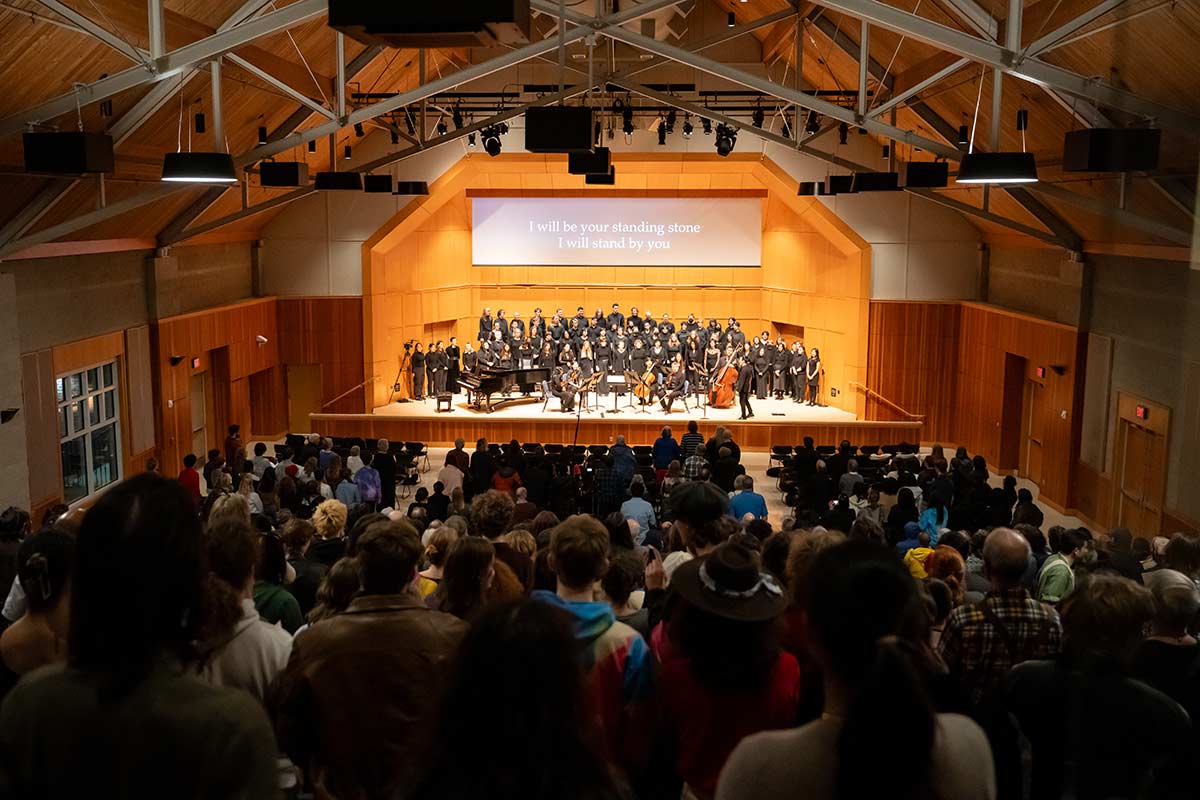 A view from the back of a large audience of a full orchestra on stage