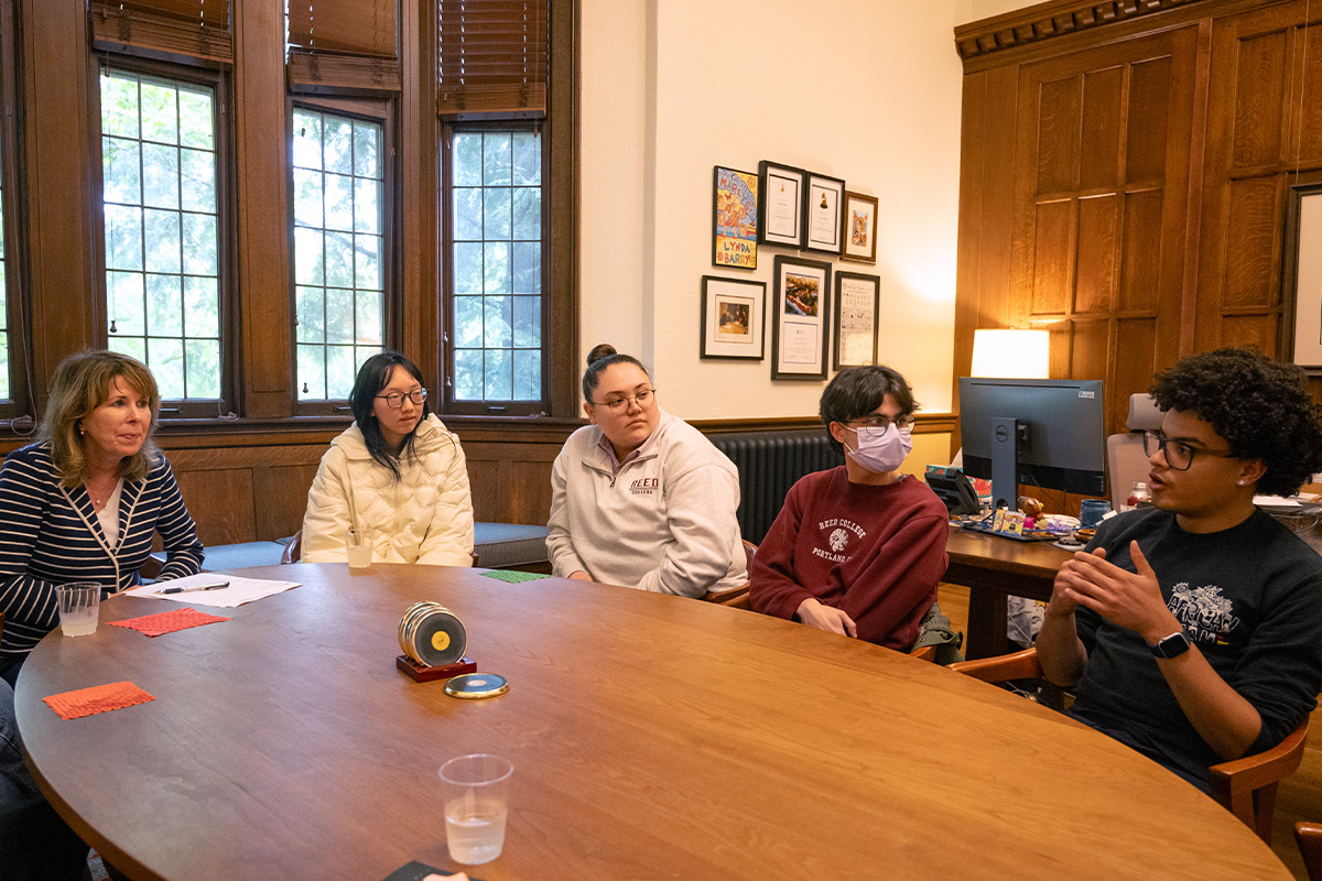 President Audrey Bilger sitting at a table with students. 