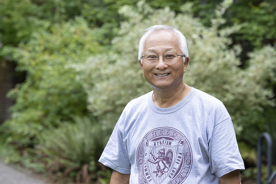 Professor Hyong Rhew smiling while standing outside on the Reed campus.