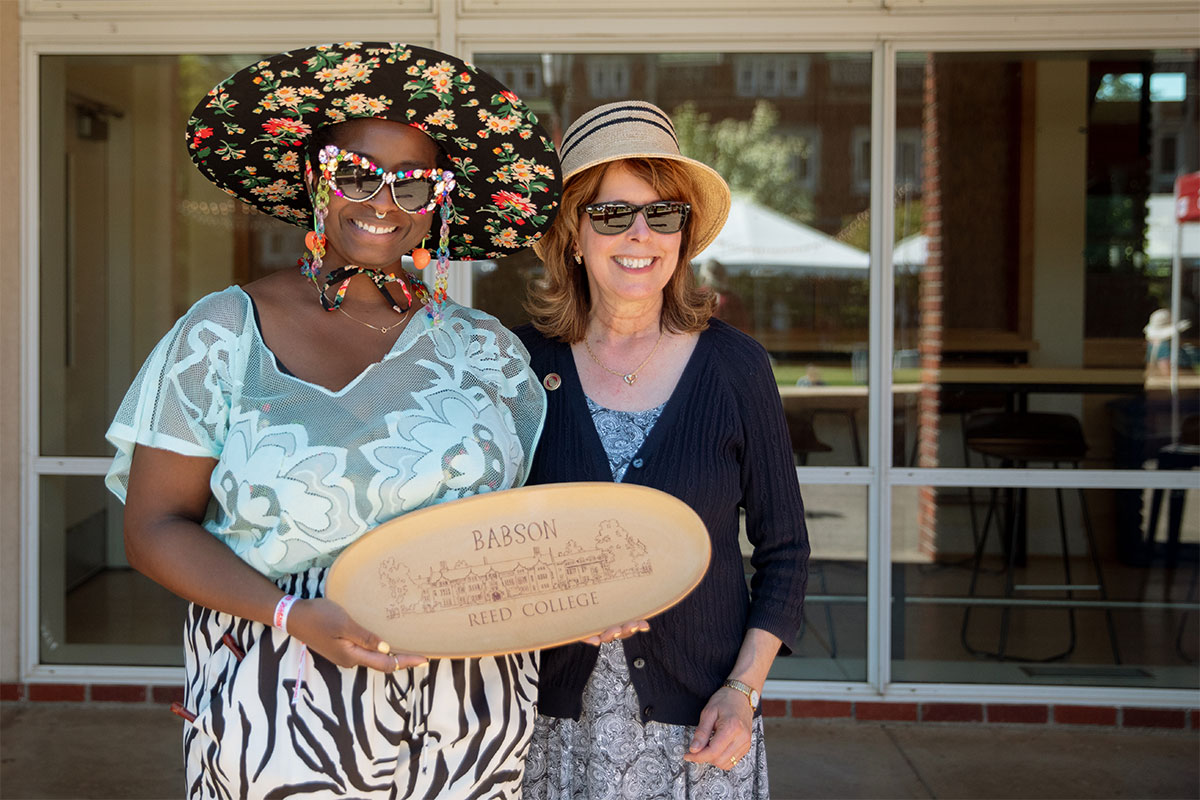 alea adigweme and Audrey Bilger stand with a wooden engraved Babson Award in front of Commons.